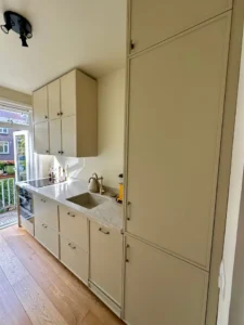 IKEA-keuken in Amsterdam met handgemaakte fronten met sierlijst, groene onderkasten en beige bovenkasten